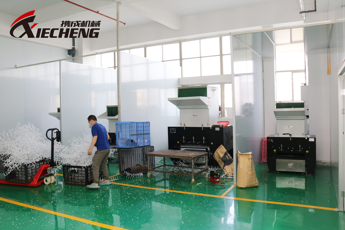 Workers manually feeding scraps into a central granulator.